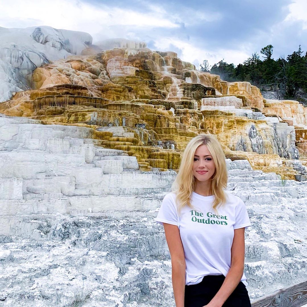 Abby Hornacek Standing Beside a Waterfall. 